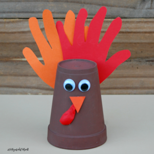 Kids using their adorable handprints to make this foam cup turkey craft for Thanksgiving.