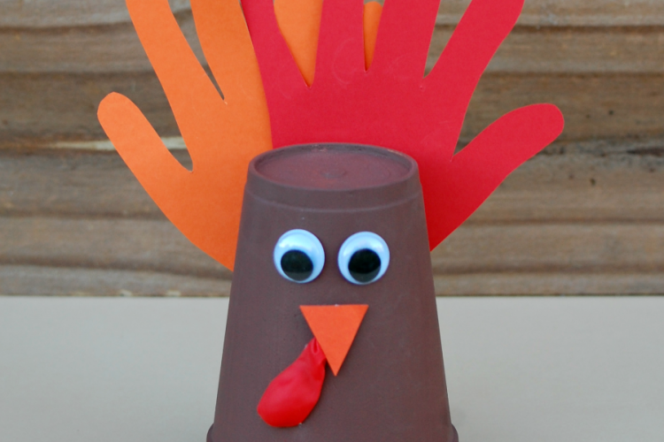 Kids using their adorable handprints to make this foam cup turkey craft for Thanksgiving.